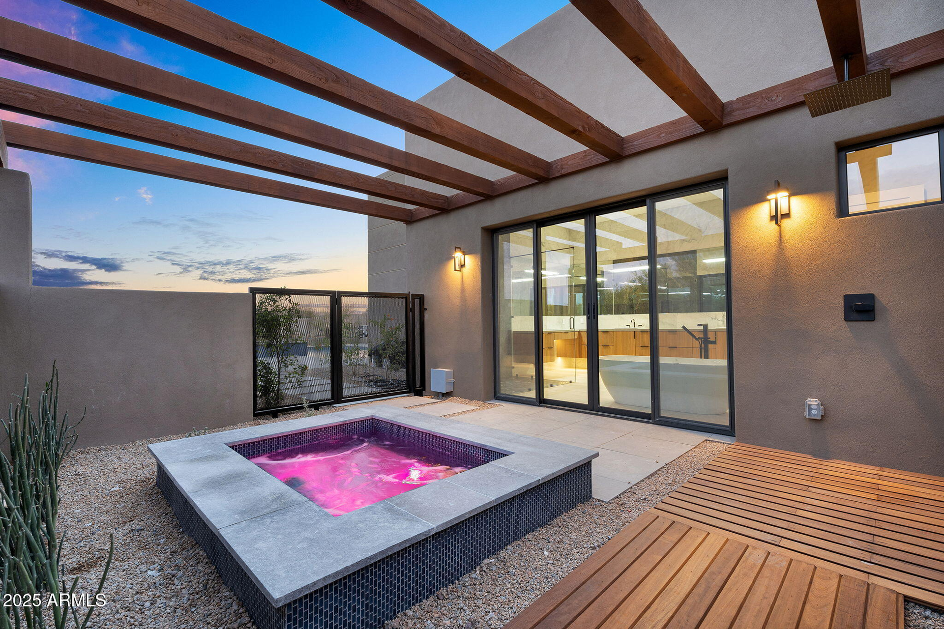 A patio with a hot tub and a wooden deck