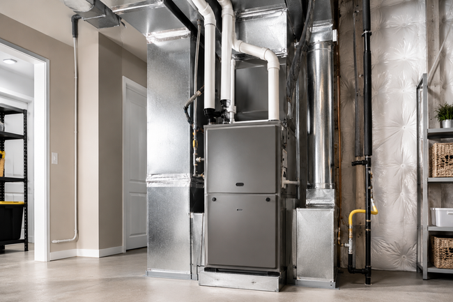 Basement utility room with HVAC furnace and ductwork, metal pipes, and concrete floor