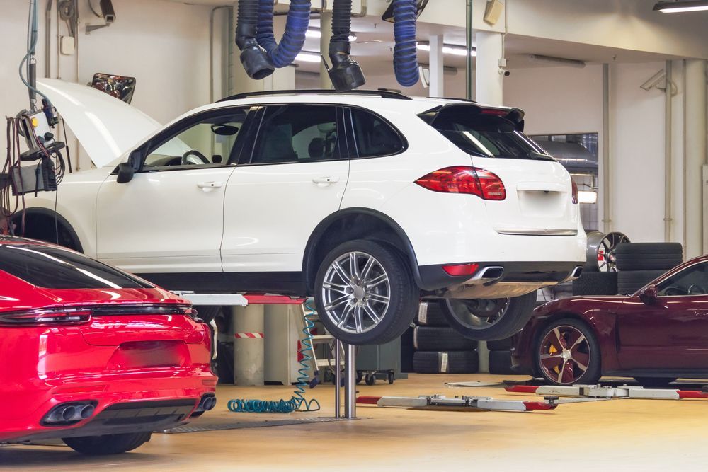 A White Porsche SUV on a Lift Inside a Professional Automotive Repair Shop — TasMech Auto Services In Mornington, TAS