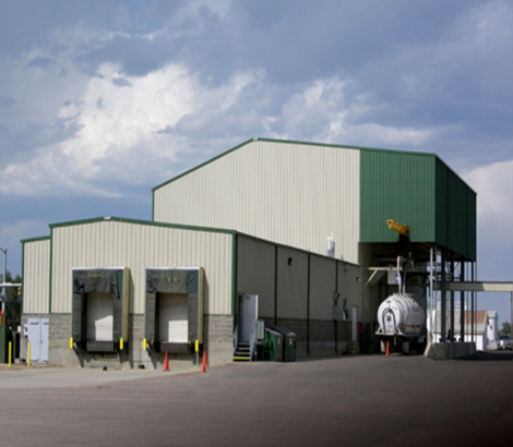 A large white building with a green roof and a truck parked in front of it