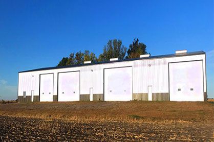 A row of white garage doors are lined up in a field