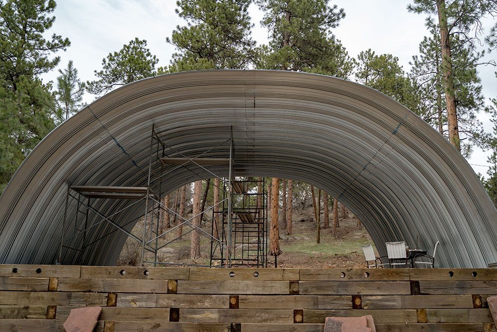A large metal structure is being built in the middle of a forest.