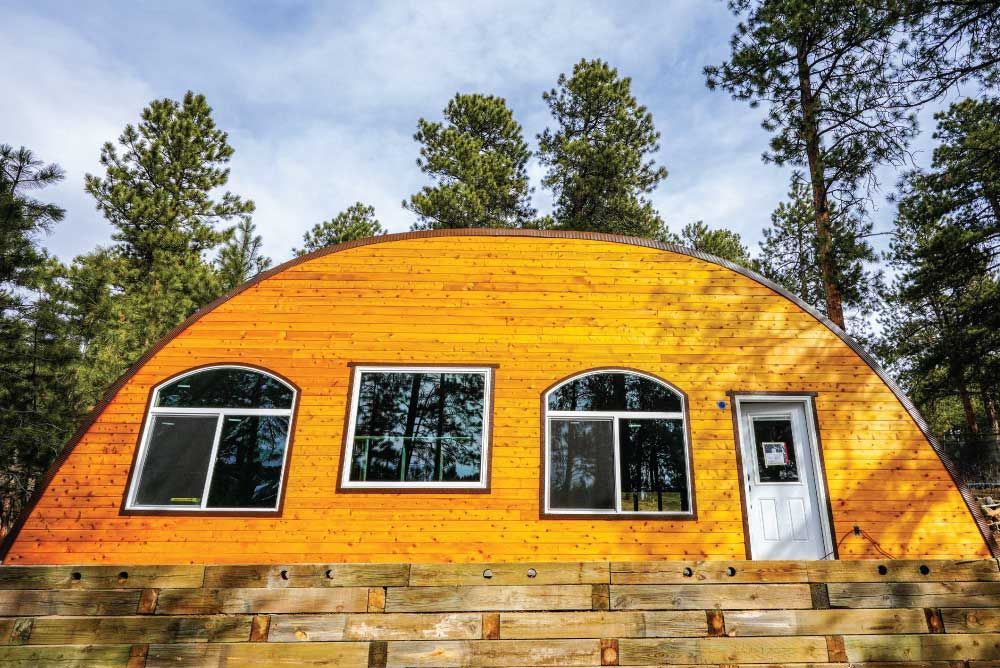 A yellow house with arched windows is surrounded by trees.