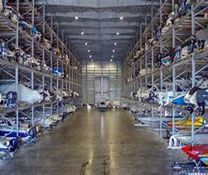 A large warehouse filled with lots of boats and jet skis.