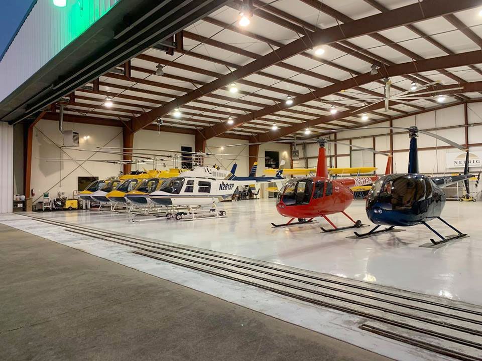 A row of helicopters are parked in a hangar.
