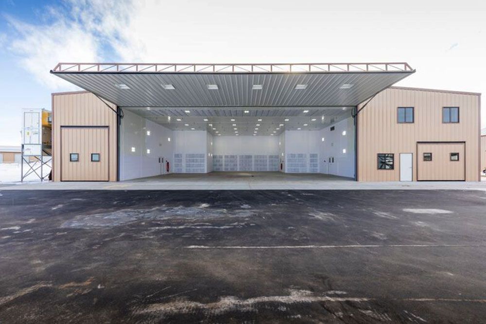 A large building with a lot of doors open and a parking lot in front of it.