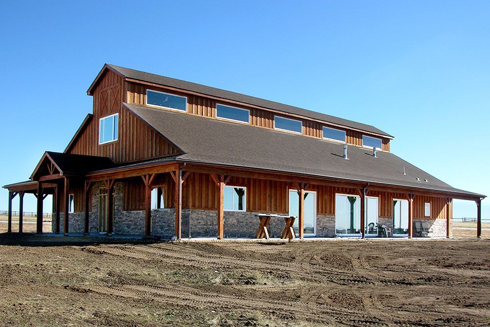 A large wooden barn with a porch in the middle of a dirt field