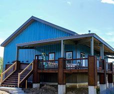A blue house with a large deck and stairs leading up to it.