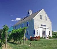 A blue and white barn with a table and chairs in front of it.