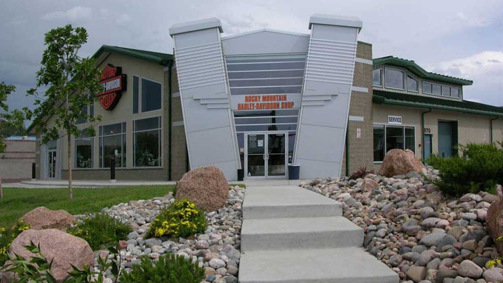 A harley davidson store is surrounded by rocks and grass