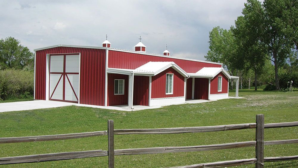 A red and white barn with a wooden fence in front of it