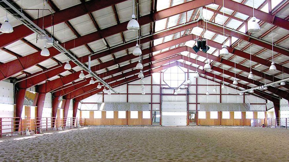 A large indoor riding arena with a red roof