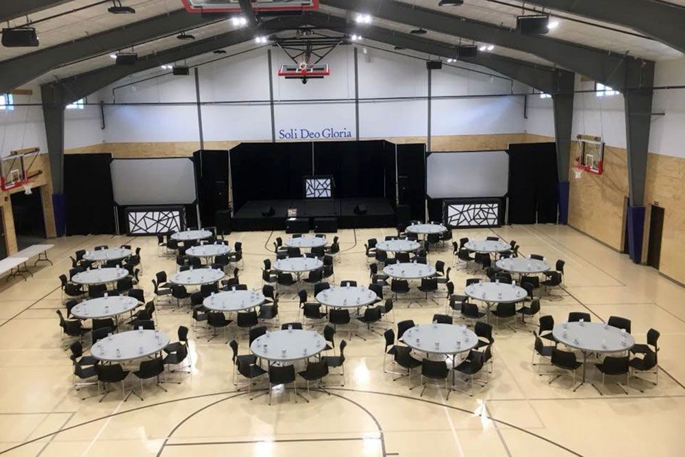 A large gym with tables and chairs set up for a banquet.