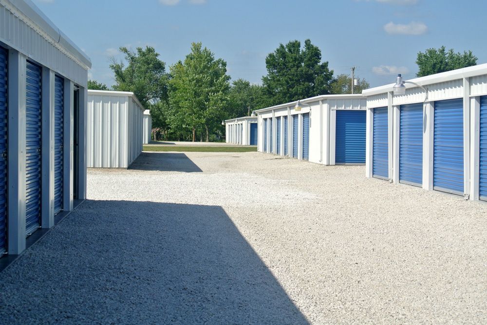 A row of storage units with blue doors on a gravel driveway