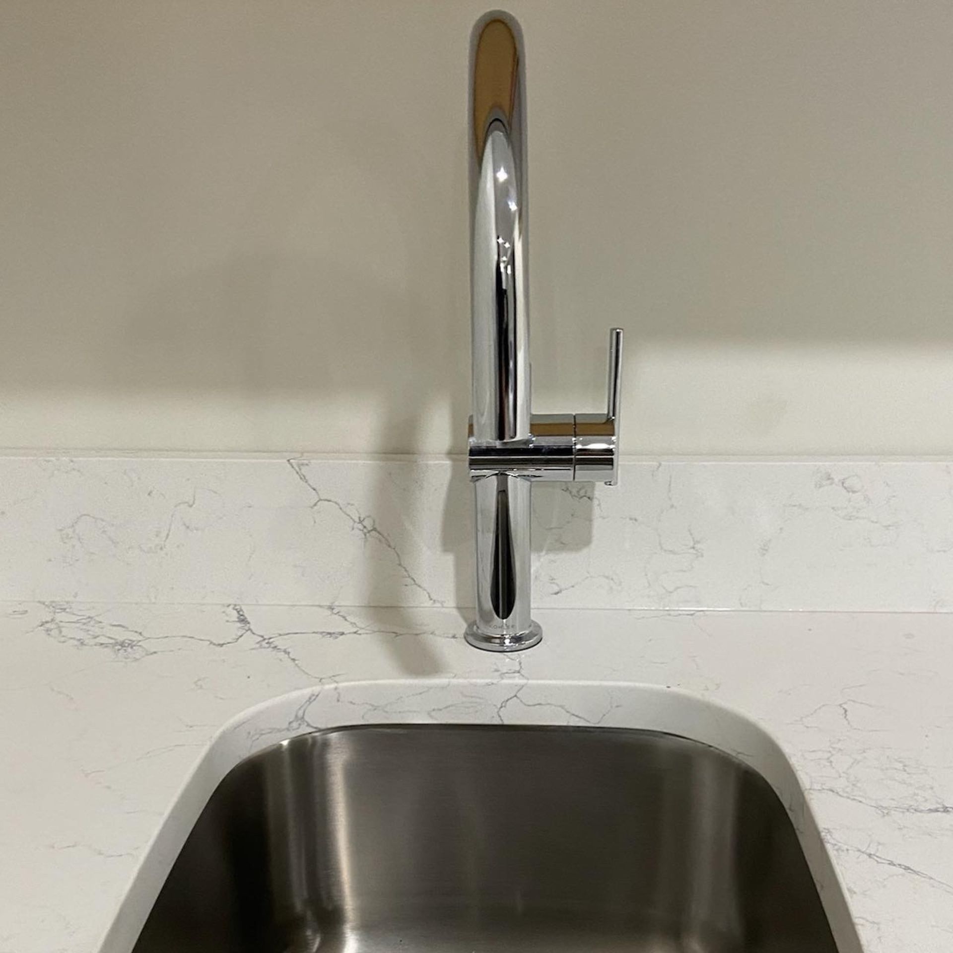 A stainless steel kitchen sink with a chrome faucet