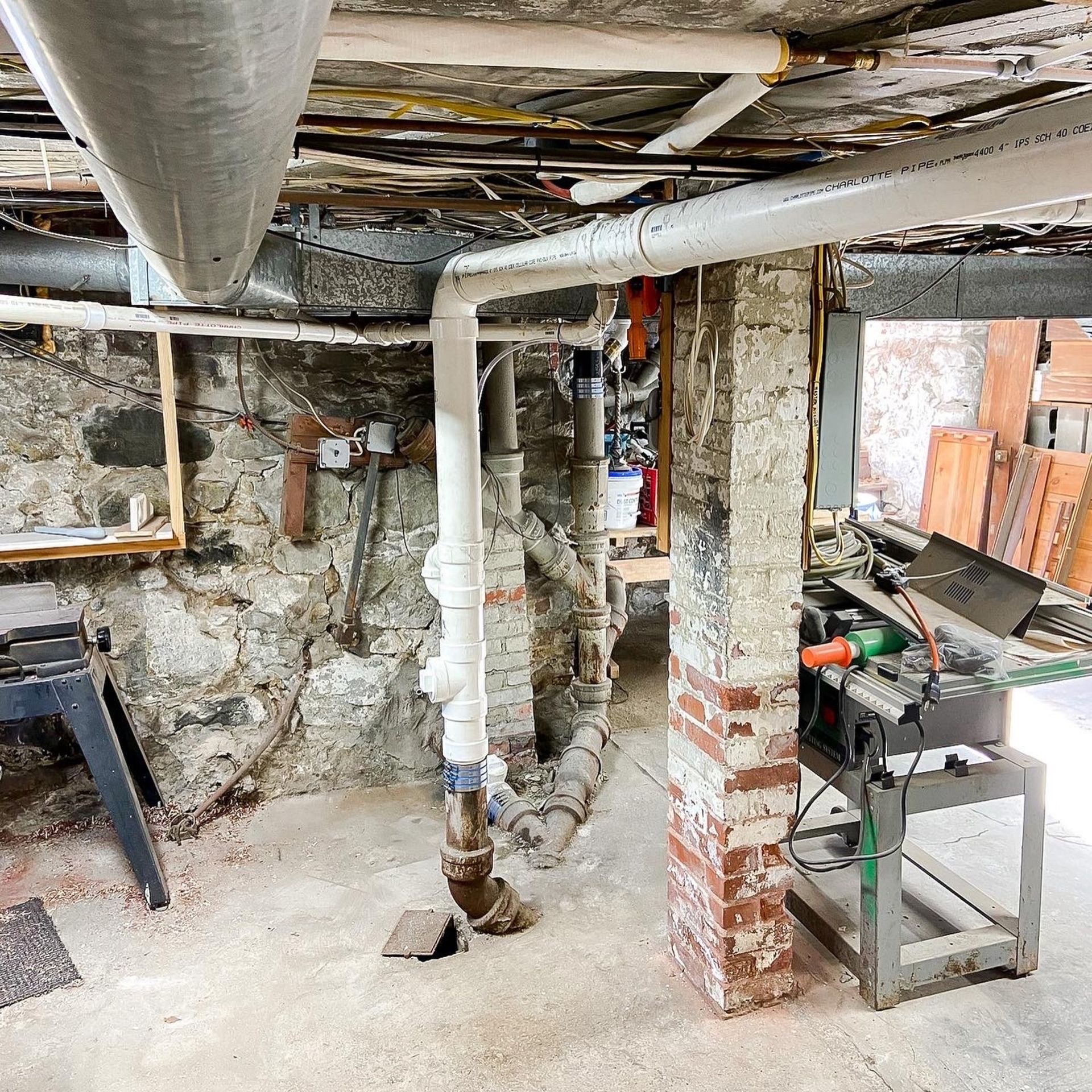 A basement with a lot of pipes and a brick wall.