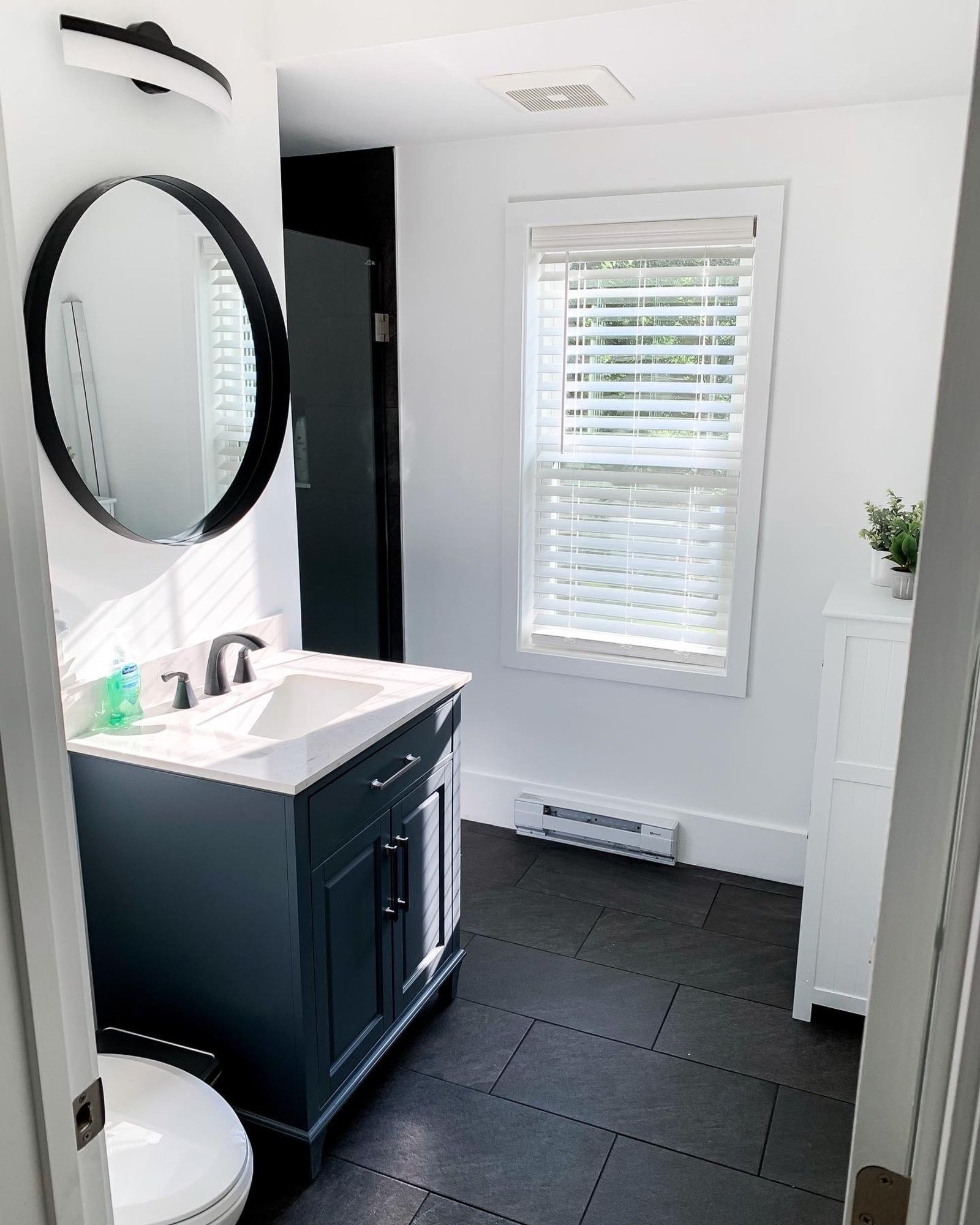 A bathroom with a sink , toilet , mirror and window
