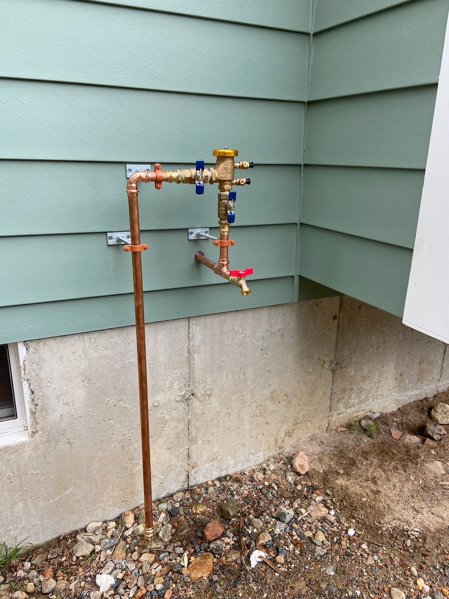 A water faucet is attached to the side of a house.