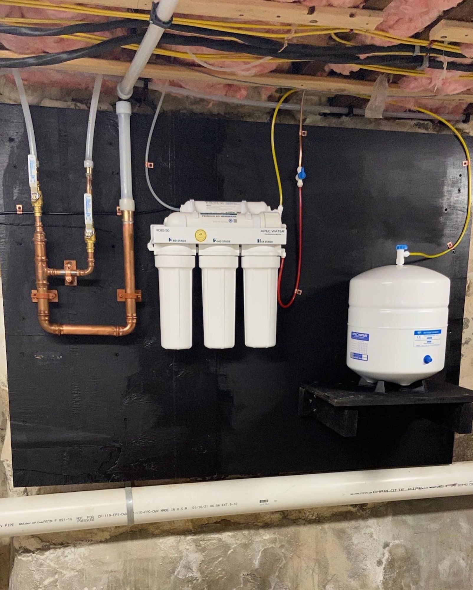 A water filter is hanging on a wall in a basement.