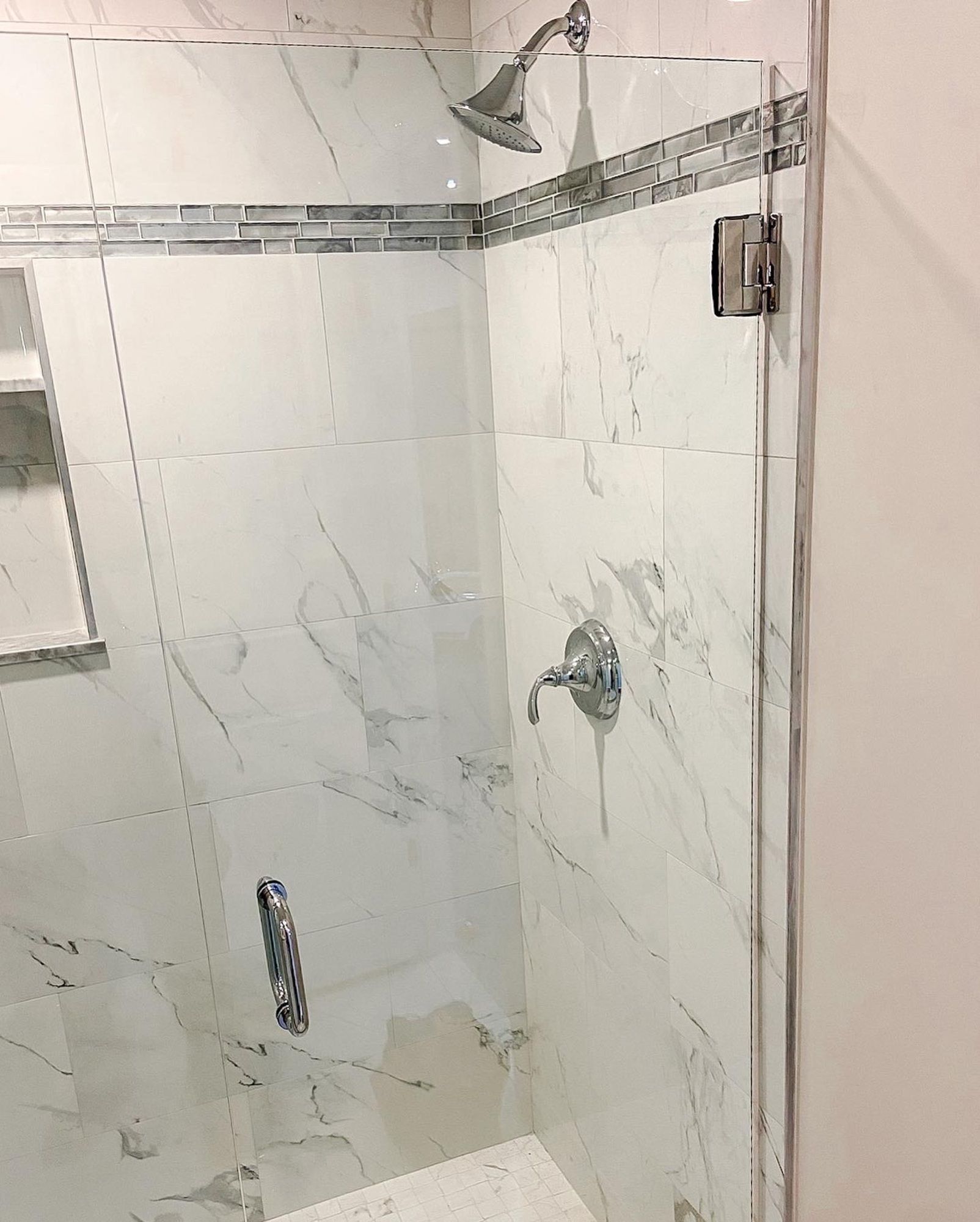 A shower stall with a glass door and a shower head.