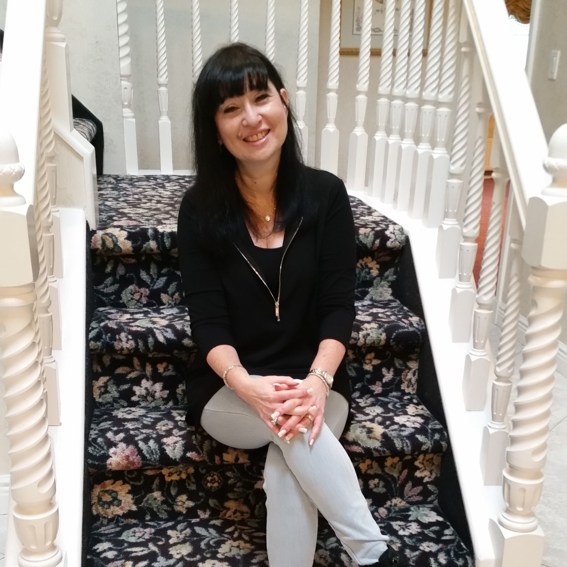 A woman is sitting on a set of stairs and smiling