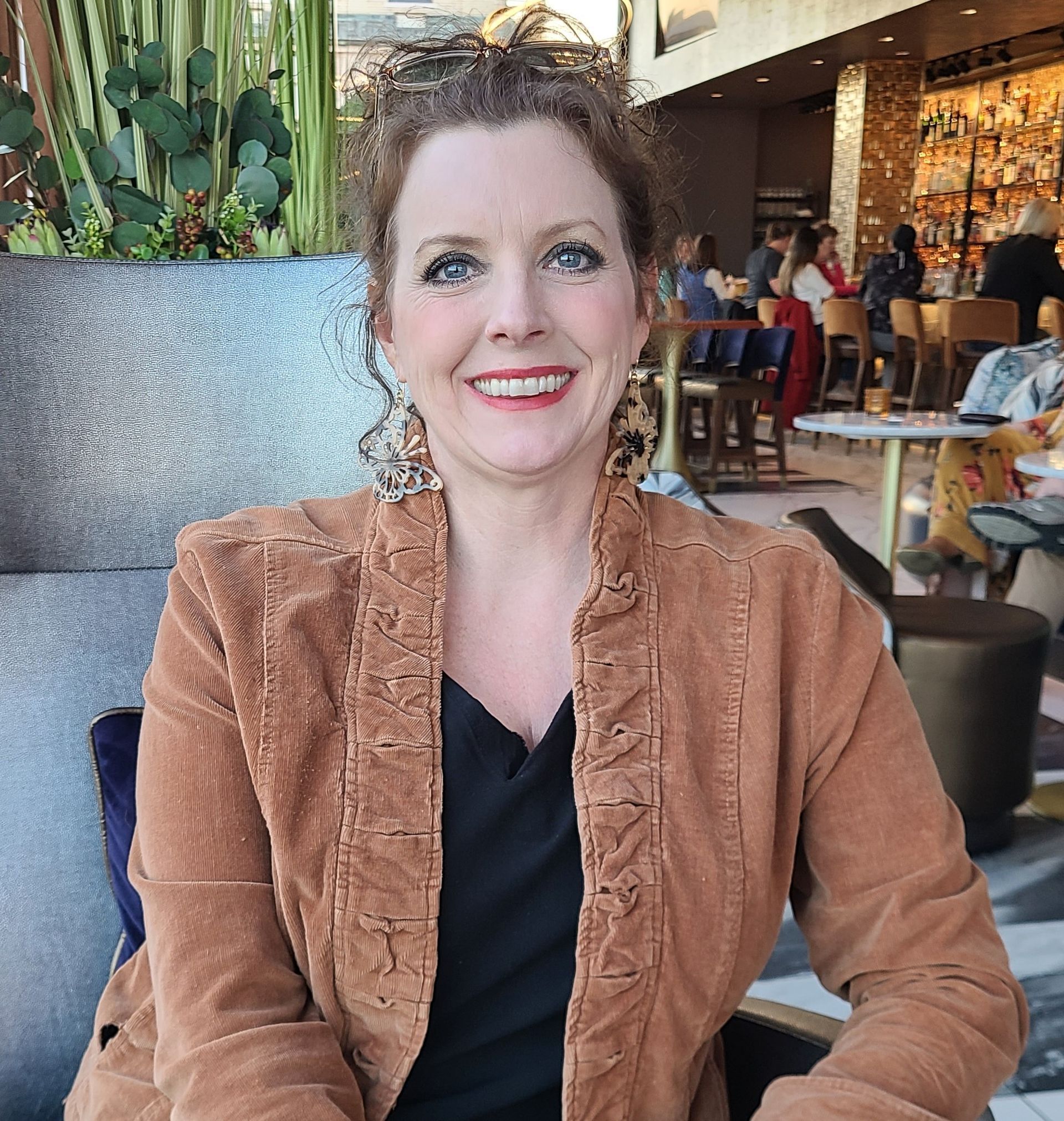 A woman in a brown jacket is smiling in a restaurant