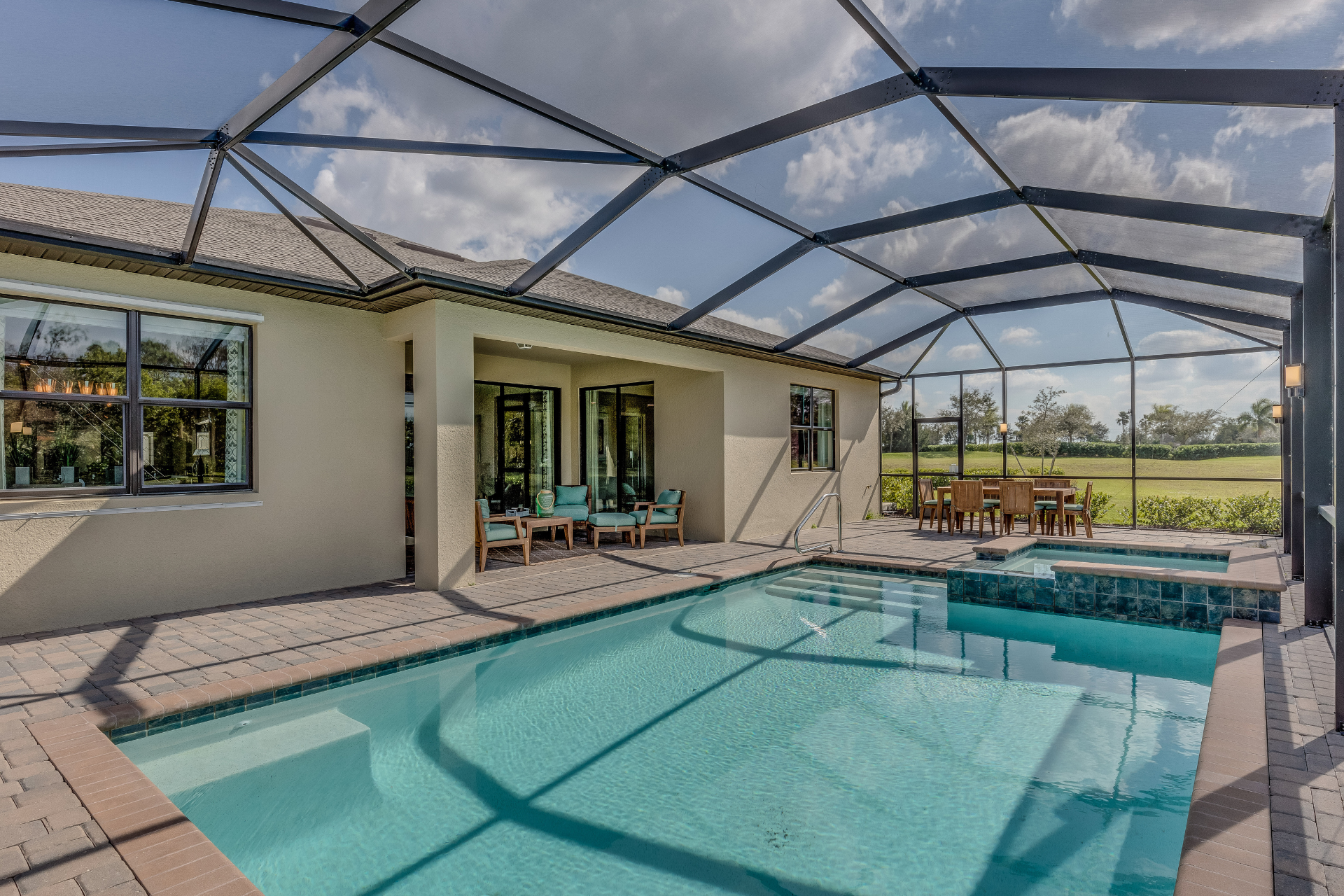Screened-in backyard pool with patio and lounge chairs beside a house