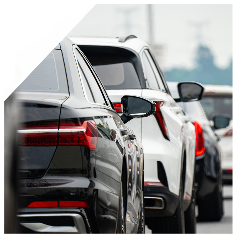 Black sedan and white SUV in traffic, close-up of rear ends, side mirrors visible.