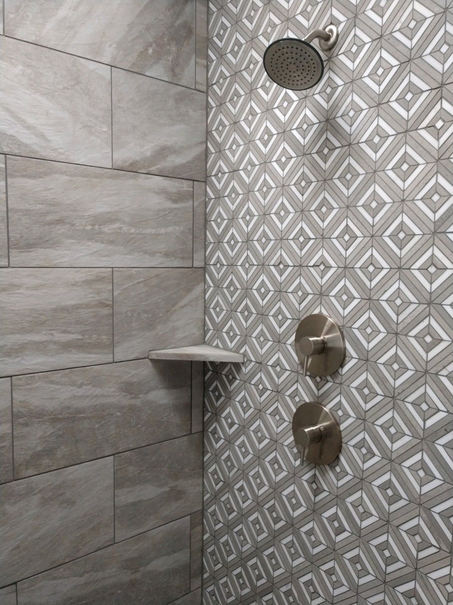 A shower with a geometric pattern on the wall and a shower head.