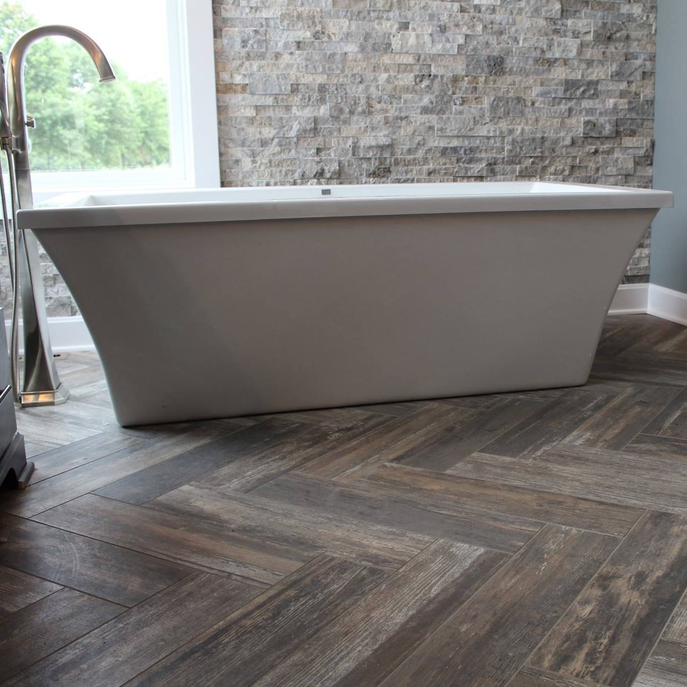 A bathtub is sitting on a wooden floor in a bathroom.