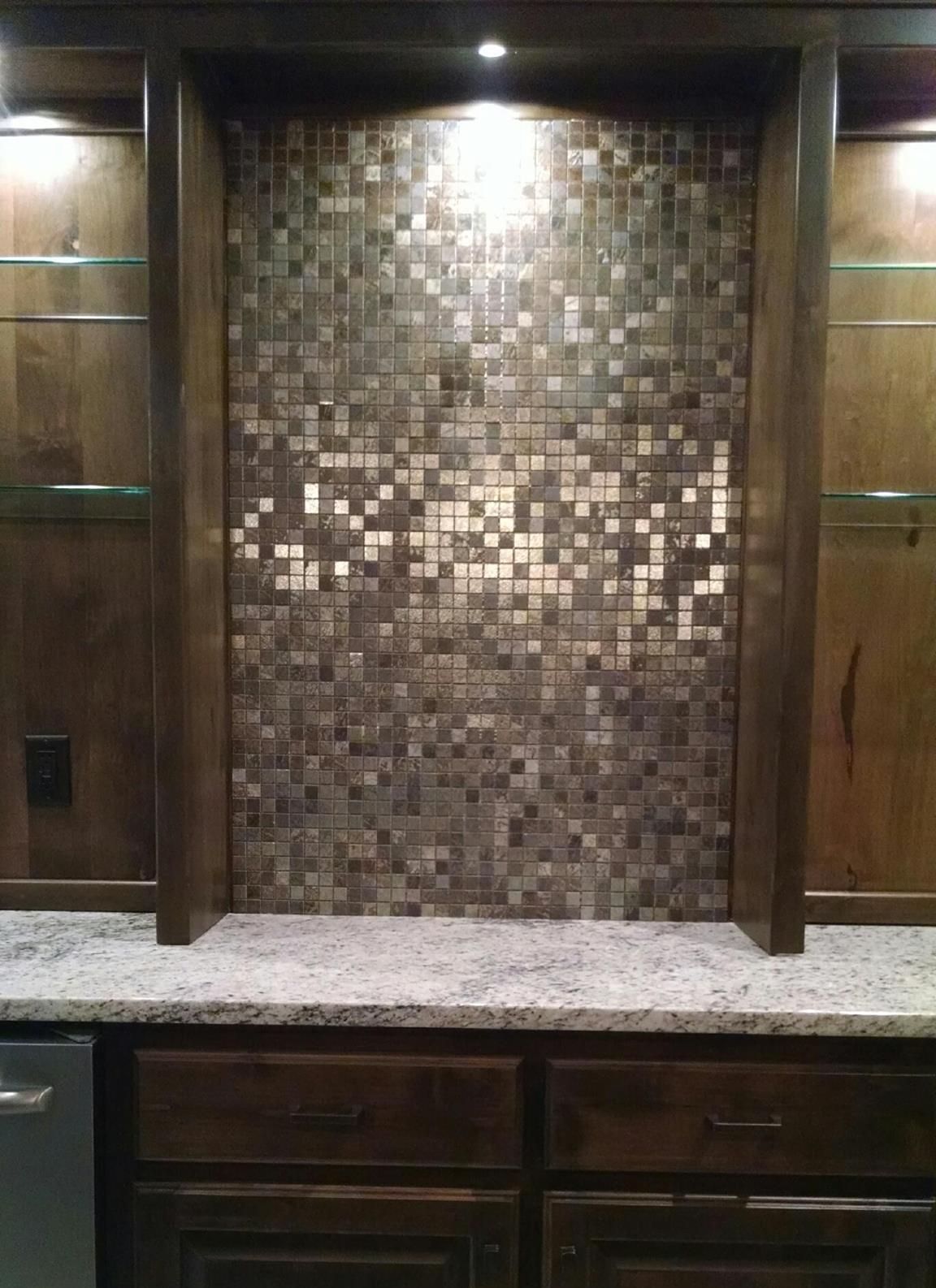 A kitchen with a mosaic tile wall and a granite counter top.