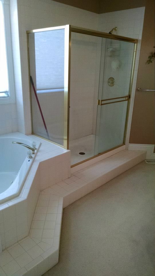 A bathroom with a tub and a shower with a sliding glass door.