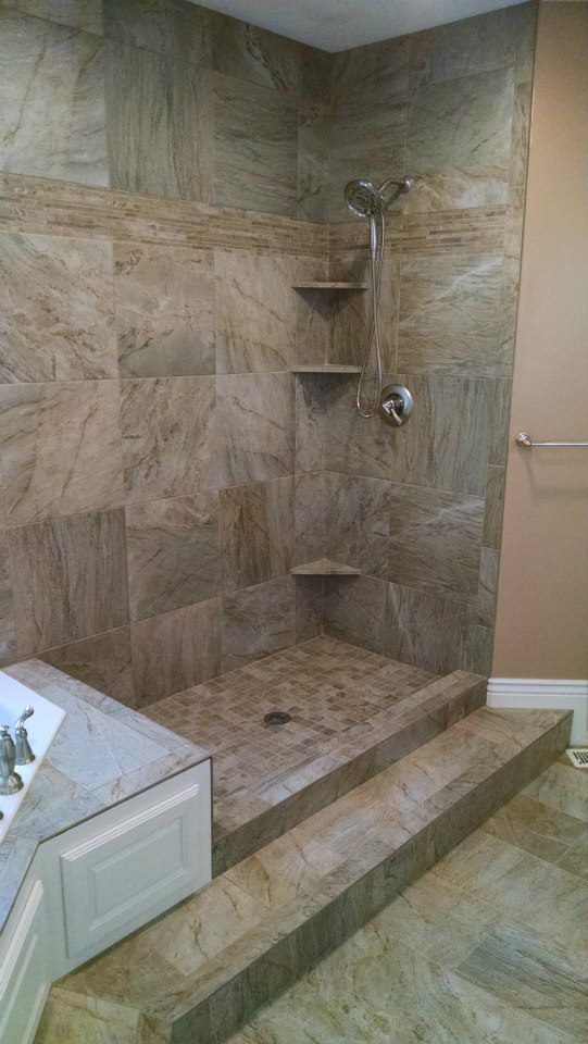 A bathroom with a walk in shower and steps leading up to it.