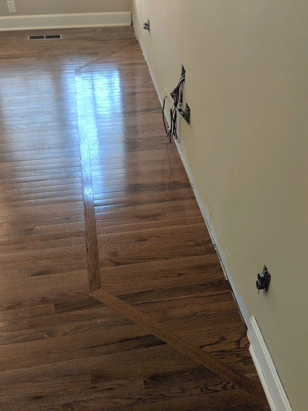 A wooden floor in a room next to a wall.