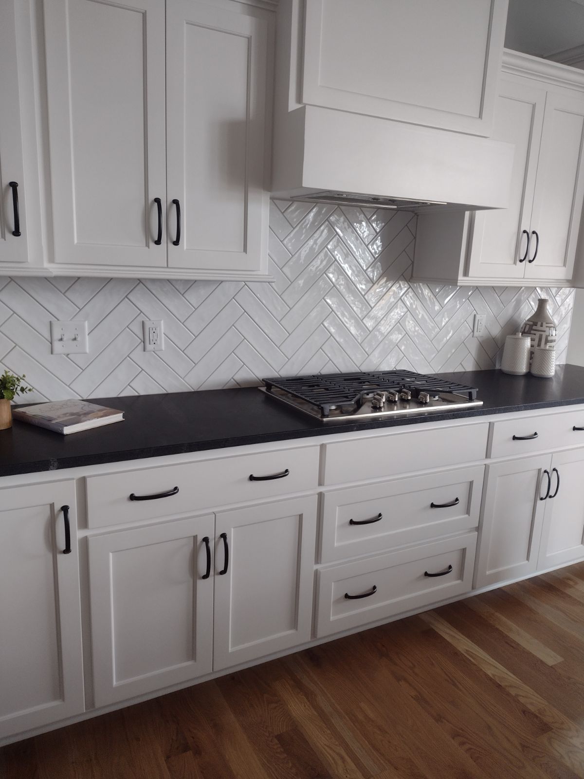 A kitchen with white cabinets , black counter tops , and a stove top oven.