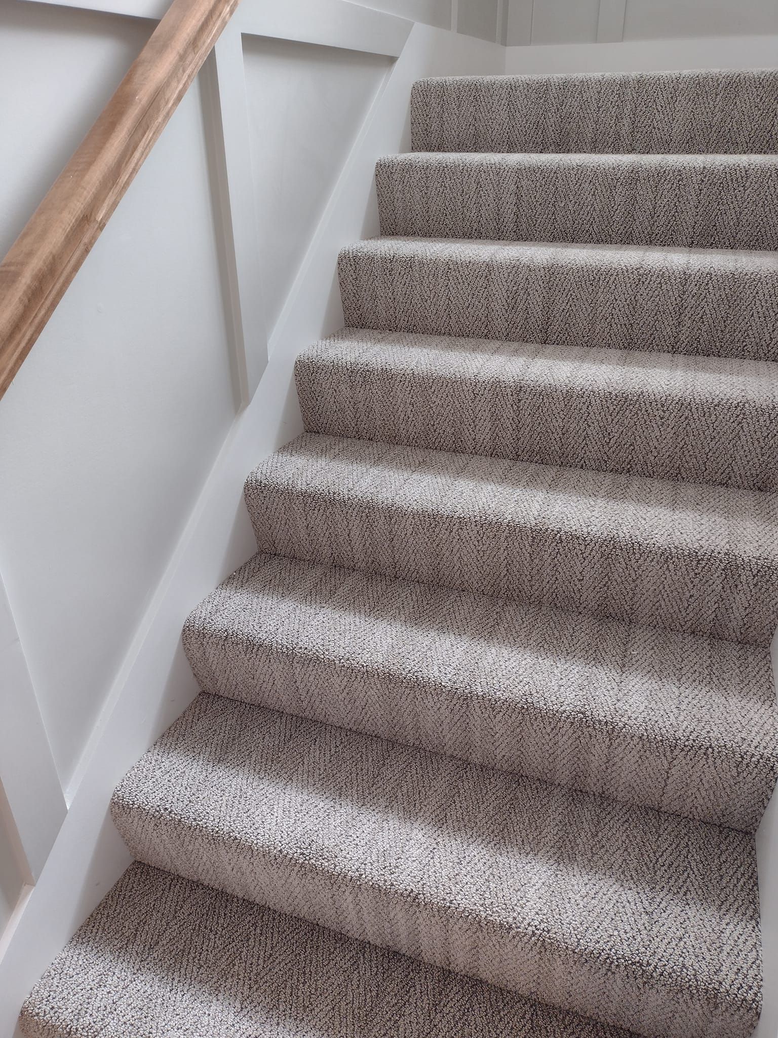 A set of stairs with carpeted steps and a wooden railing.