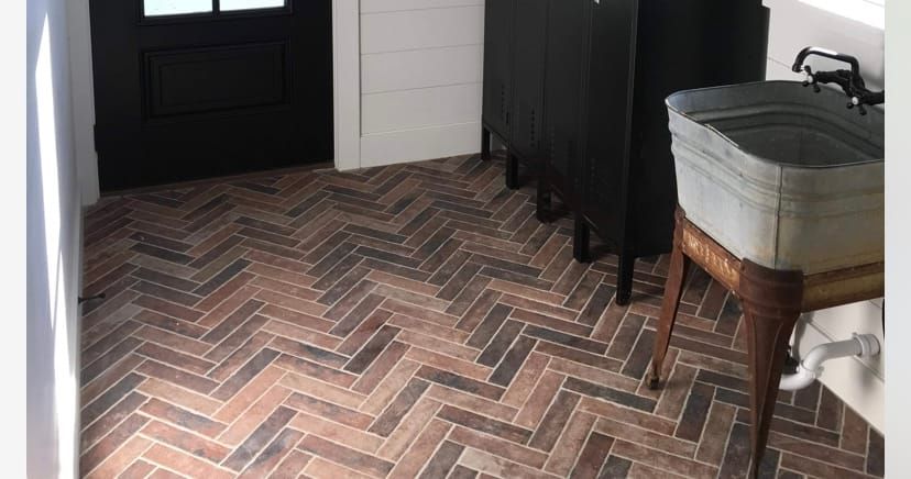 A bathroom with a herringbone tile floor and a sink.
