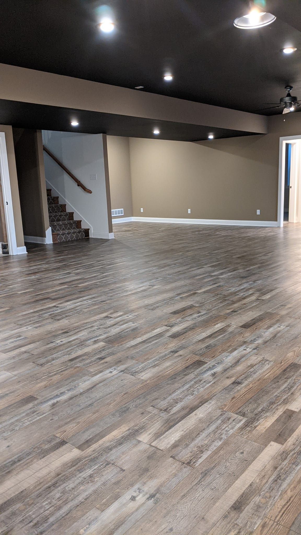 A large empty basement with wooden floors and stairs.