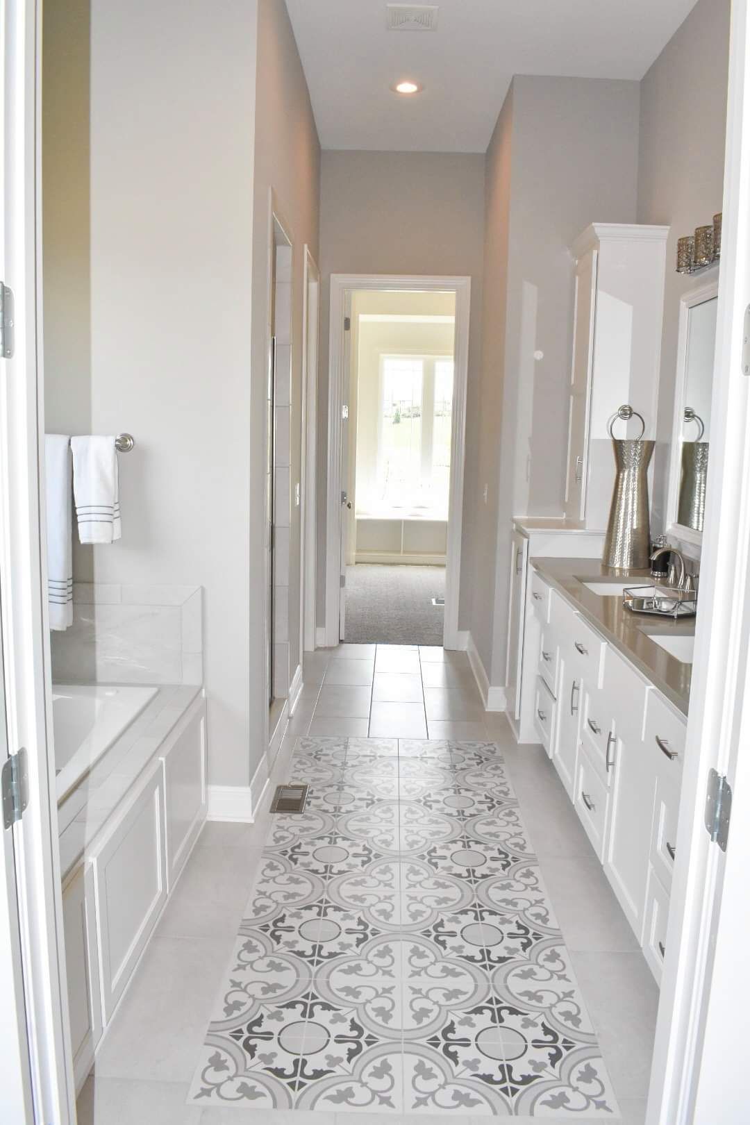 A bathroom with a long hallway leading to two sinks and a bathtub.