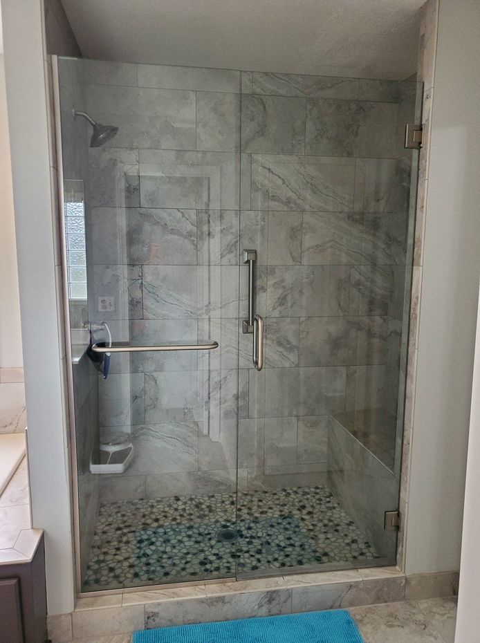 A bathroom with a walk in shower with a glass door.