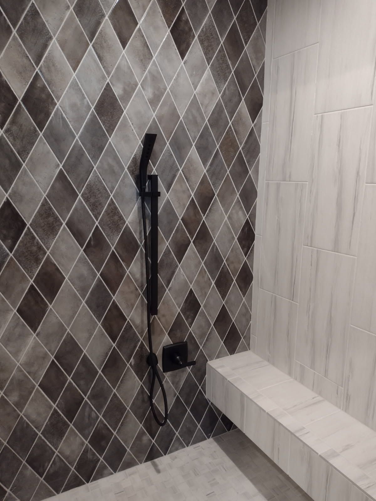 A shower with a bench and a shower head on the wall.