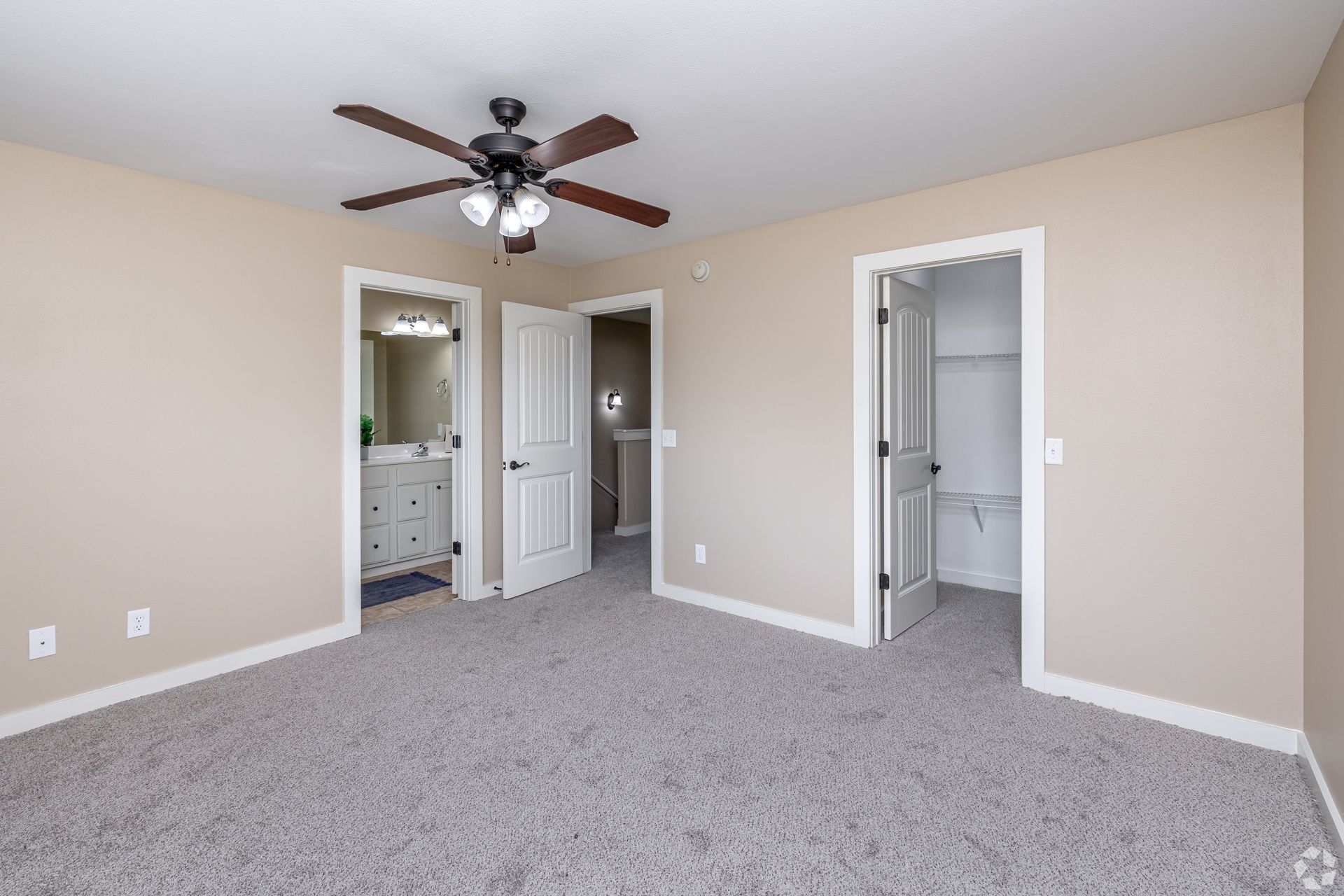 Bedroom with carpet, three doorways, and a ceiling fan.
