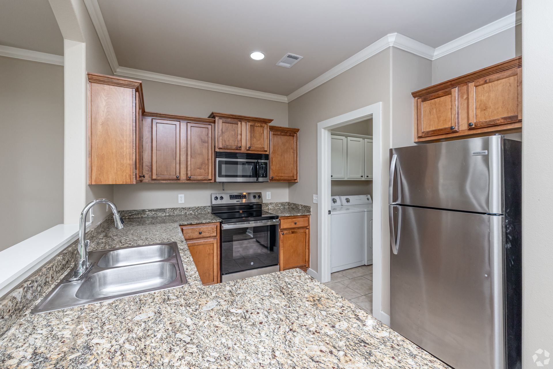Kitchen with wooden cabinets, stainless steel appliances, and granite countertops.