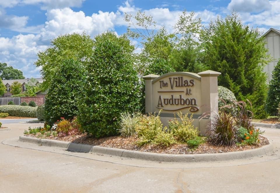 A sign for the villas at audubon is surrounded by trees and bushes