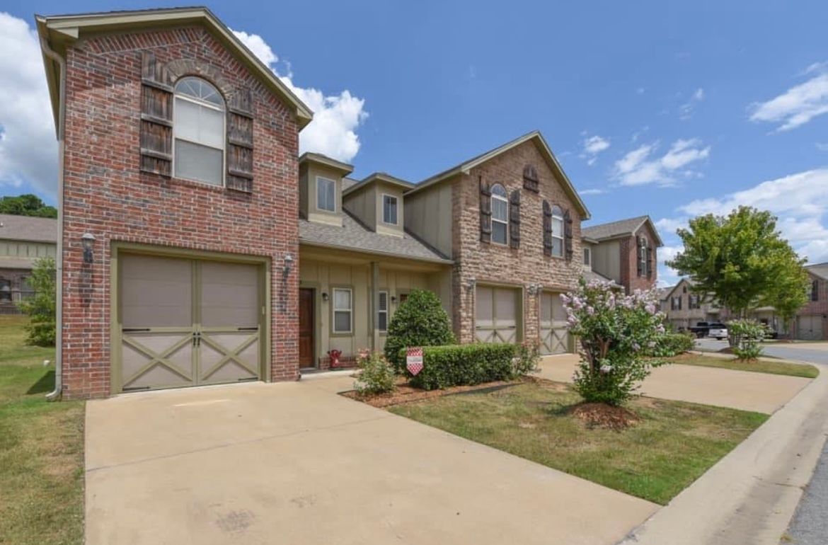 A row of brick houses with a concrete driveway in front of them.