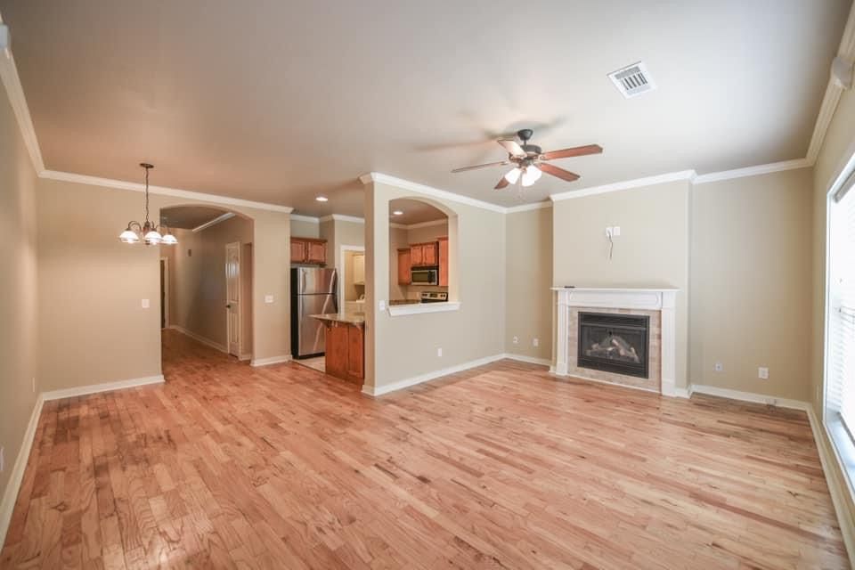 An empty living room with hardwood floors and a fireplace.