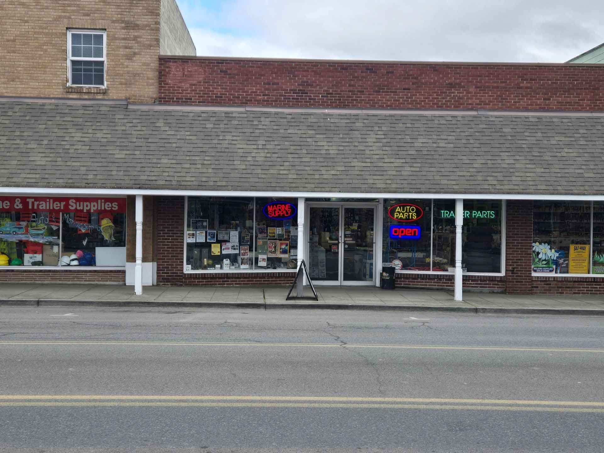 Storefront with brick facade, display windows with neon signs, and a street view.