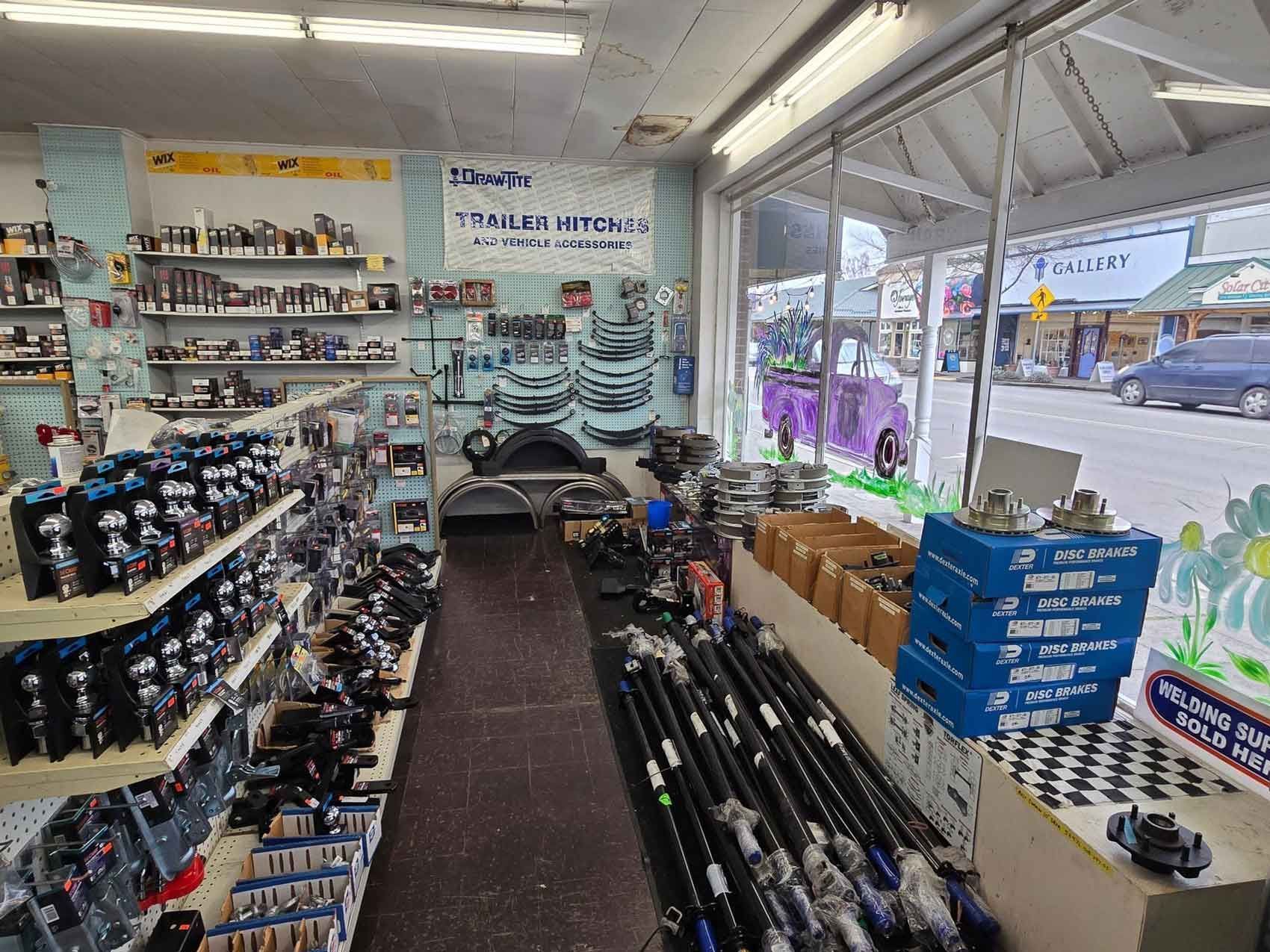 Auto parts store interior with shelves of parts and window view of a street.