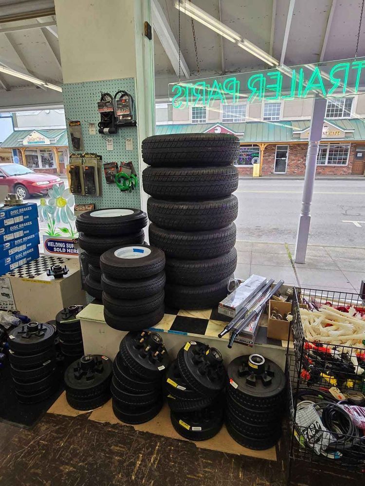 Tires and trailer parts for sale inside a shop. A large stack of tires is in the center.