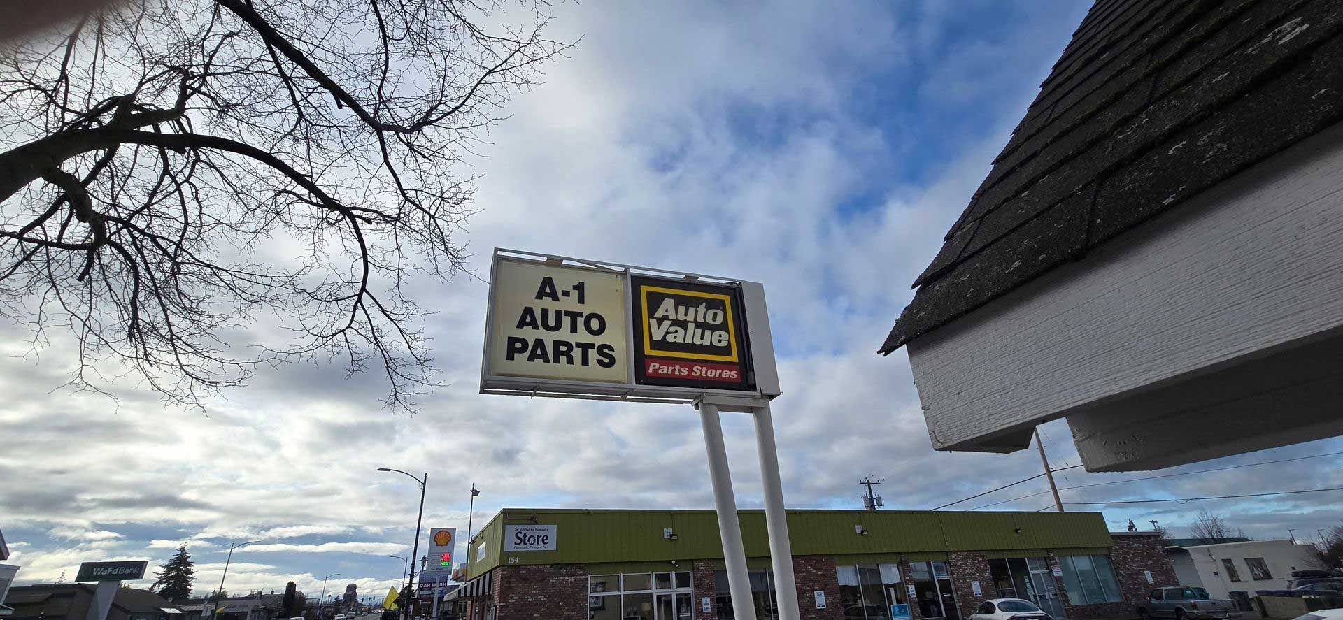 Sign for A-1 Auto Parts, with a building and cloudy sky in the background.